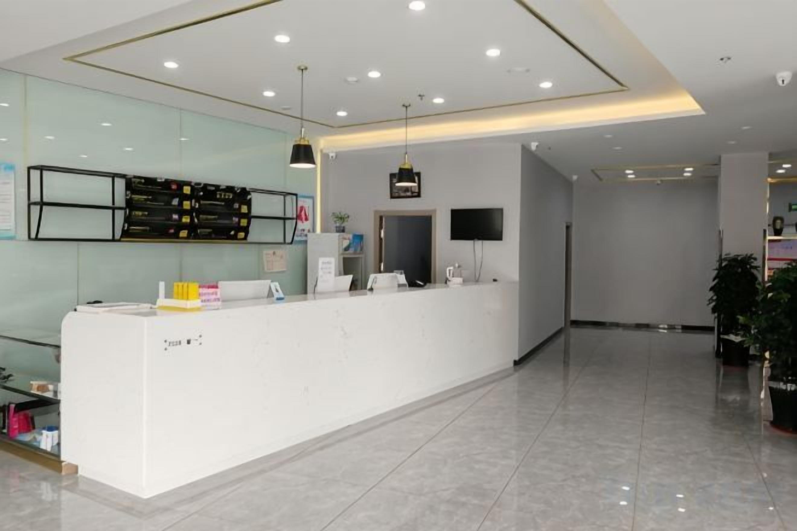 A reception area with a white reception desk, a flat-screen TV, and a glass wall.
