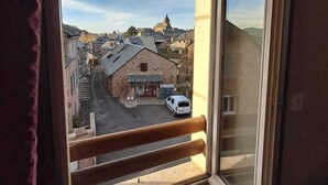A window with a view of a town, a building with a sign, and a white van parked outside. - le relais de lassouts (Lassouts)