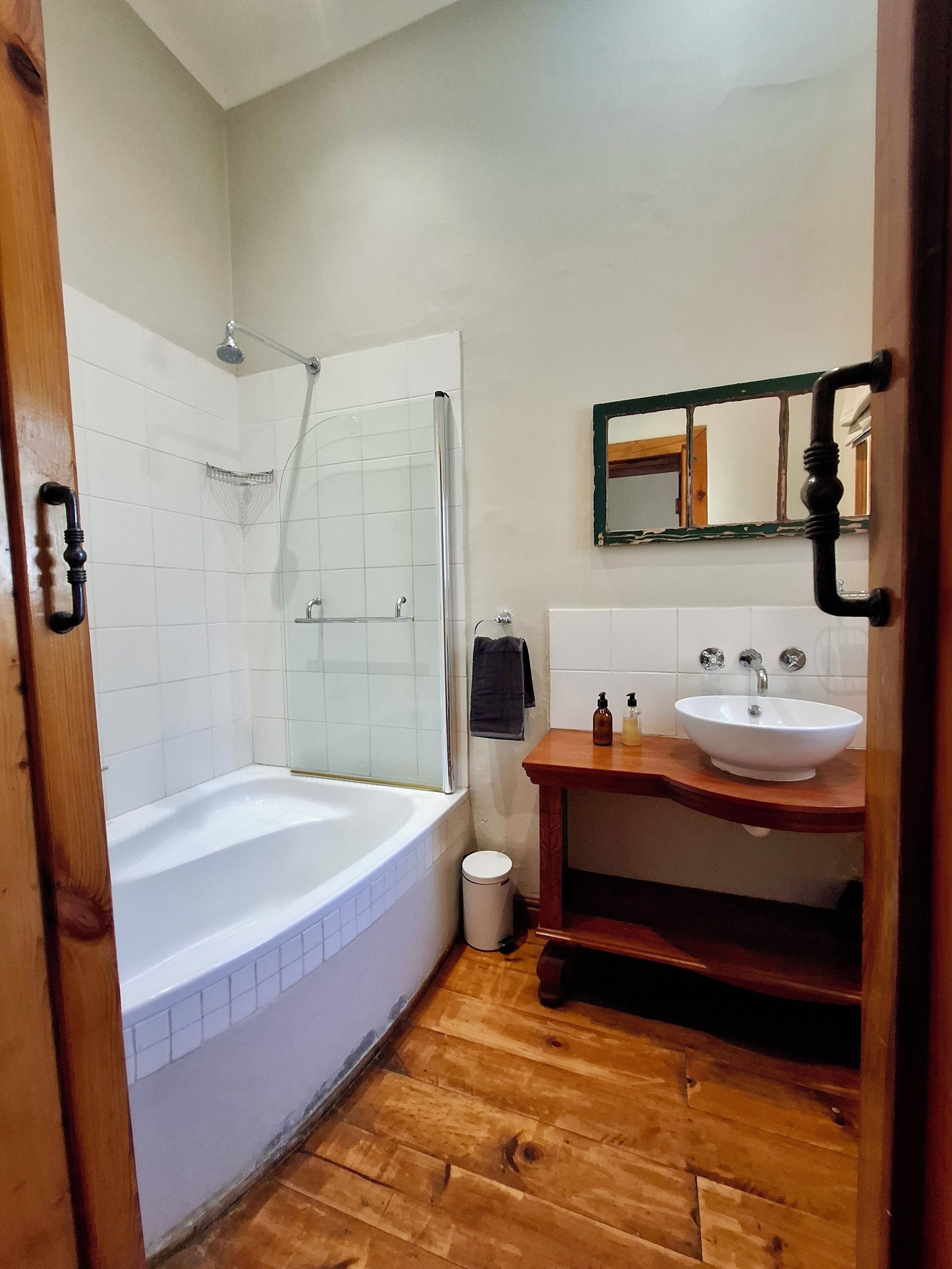 Een badkamer met een bad, wastafel en spiegel.