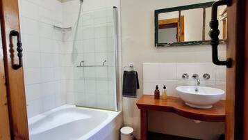 Een badkamer met een bad, wastafel en spiegel.