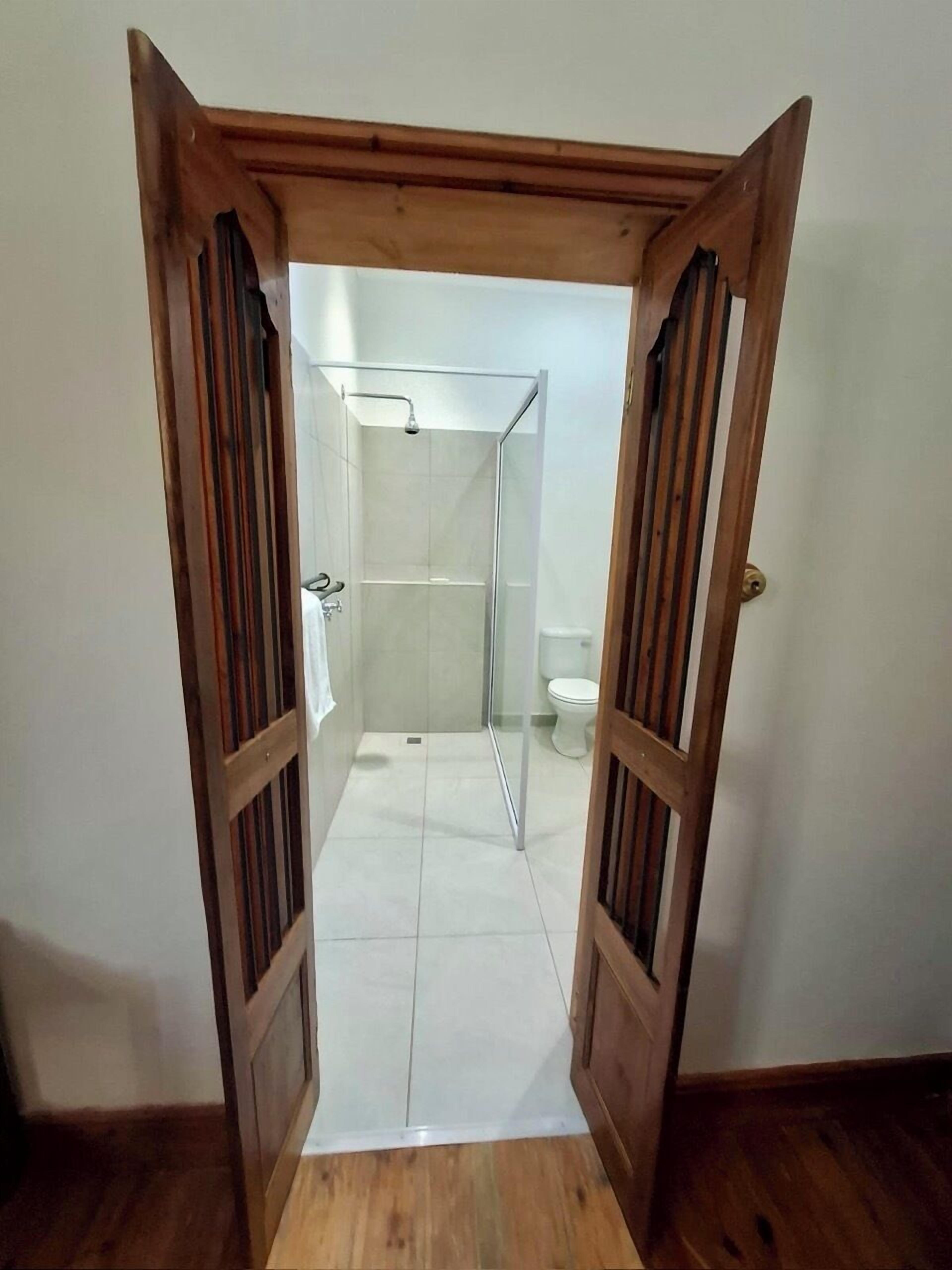 A doorway leading to a bathroom with a glass shower enclosure and a toilet.