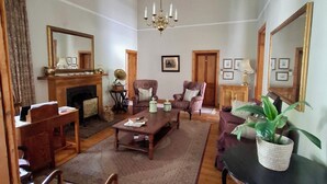 A spacious living room with a fireplace, comfortable seating, and a chandelier. - Sundays Karoo Guesthouse (Graaff-Reinet)