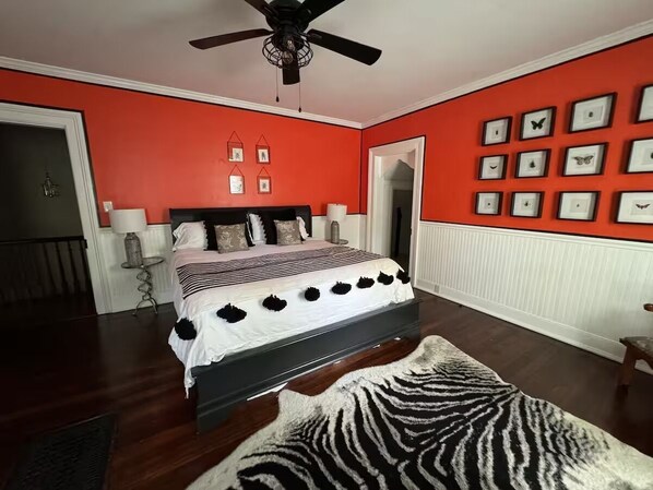 A bedroom with a bed, a ceiling fan, a zebra-patterned rug, and framed pictures on the wall. - Charming 3-bedroom house in Midway with screened in porch and salt water pool! (Midway)
