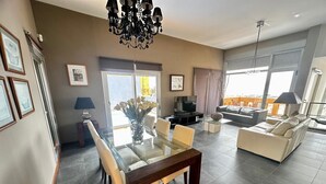 Ein modernes Wohnzimmer mit einem Glastisch, einer Couch, einem Fernseher und einer Pendelleuchte.