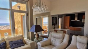 Ein geräumiges Wohnzimmer mit großem Fenster, einer Kristallleuchter und Meerblick.