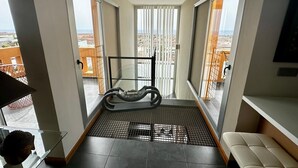 Ein Balkon mit Laufband, Glasgeländer und Blick auf die Stadtlandschaft.