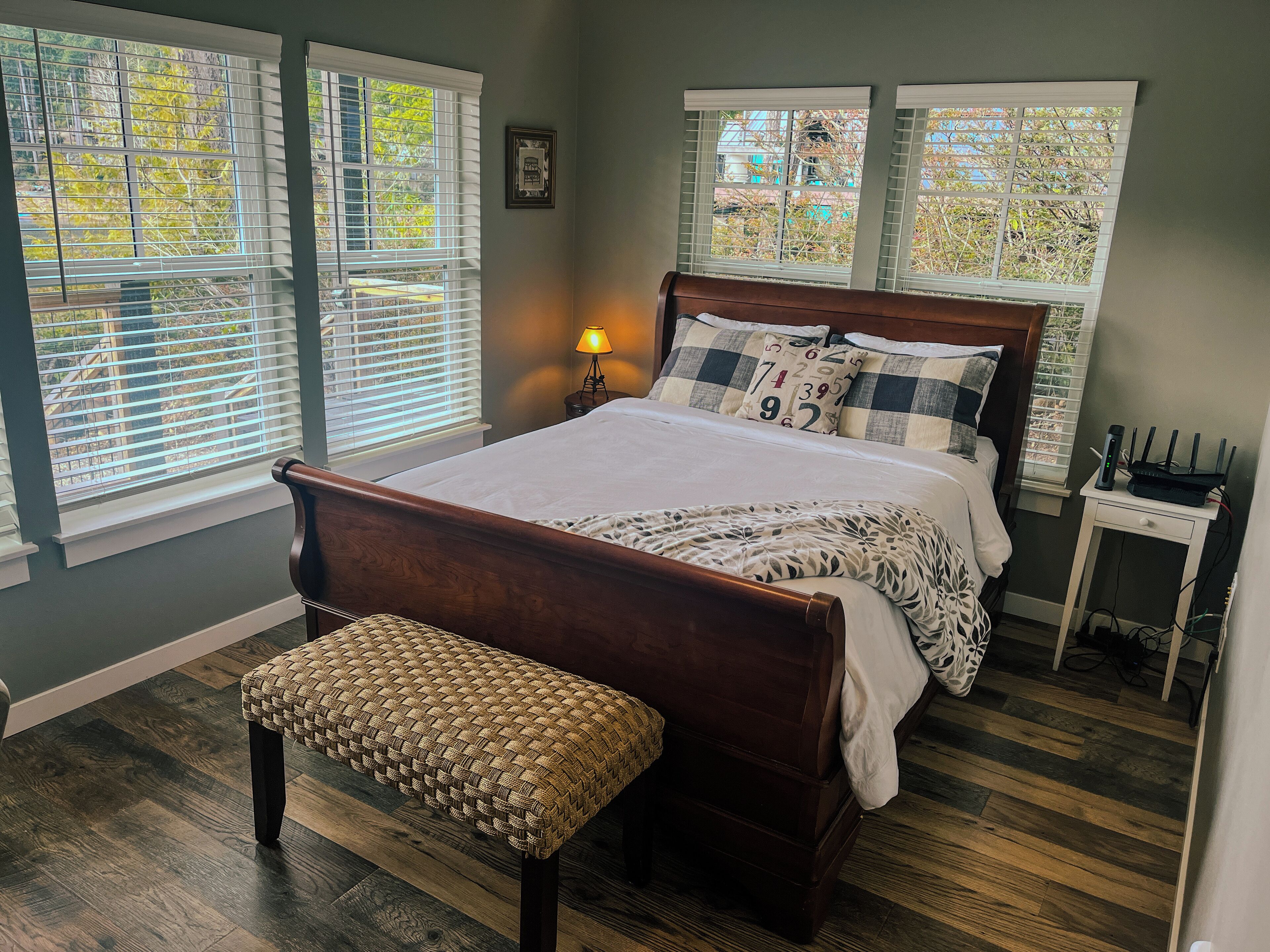 A bedroom with a wooden bed, a bench, and a nightstand with a lamp.