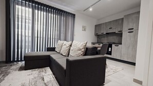 A modern living room with a sectional sofa, a dining area, and a kitchen. - Charming 1-Bedroom Apartment in Il-Gżira, Malta (Il-Gżira)