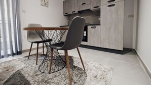 A modern kitchen with grey cabinets, a wooden dining table, and two chairs. - Charming 1-Bedroom Apartment in Il-Gżira, Malta (Il-Gżira)