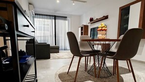 Ein moderner Essbereich mit einem runden Tisch, vier Stühlen und einer Blumenvase in der Mitte.
