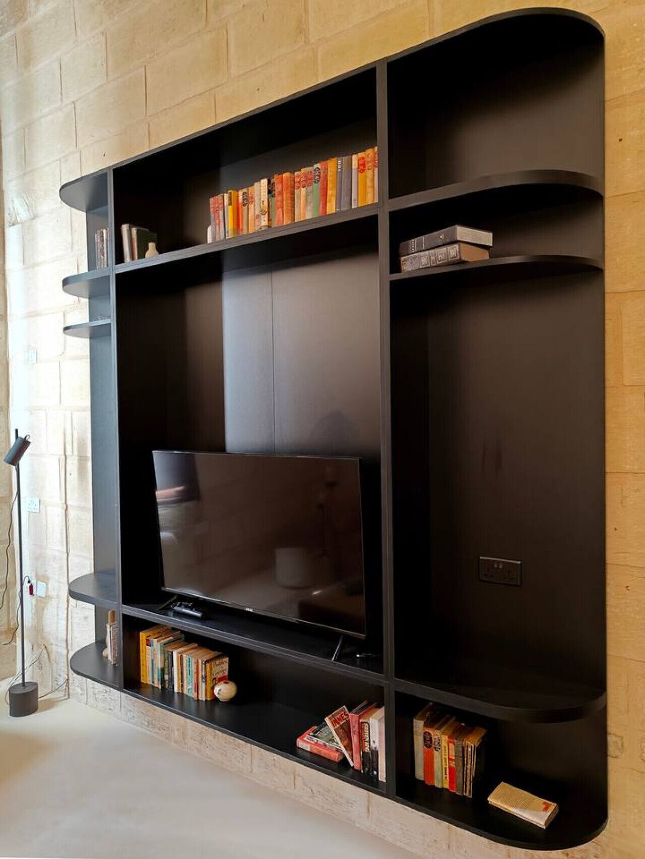 Een moderne woonkamer met een inbouwkast in het zwart, een flatscreen televisie en een open haard.