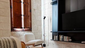 Un salon avec un canapé, une table basse, un téléviseur et une bibliothèque.