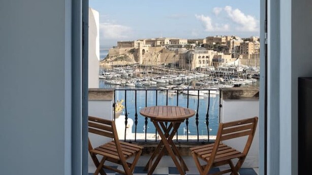 Un balcon doté d’un sol à carreaux, de deux chaises en bois et d’une petite table ronde.