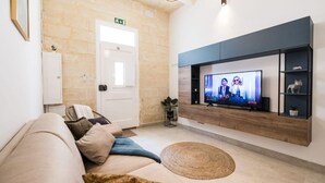 Una sala de estar moderna con un sofá, televisor y un estante fijado a la pared.
