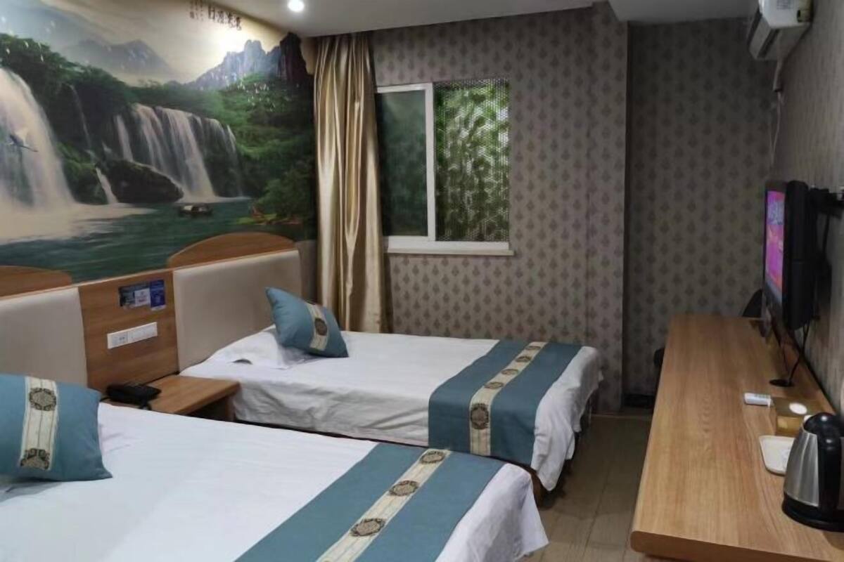 Habitación de hotel con dos camas, un escritorio, un televisor y un mural de una cascada.