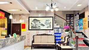 Ein Empfangsbereich mit Marmorzauber, einem traditionellen Sofa, einem kleinen Tisch und einer Treppe mit Infoplakaten.