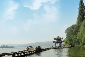 Une jetée en bois s’avançant dans un lac, avec un pavillon traditionnel à son extrémité.