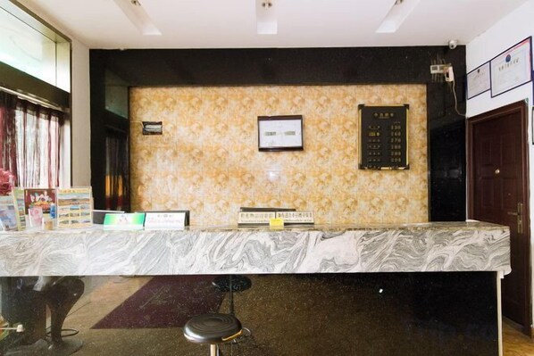 A reception desk with a marble top, a framed sign, and a wall-mounted information board. - Hangzhou Shujia Hotel (Hangzhou)