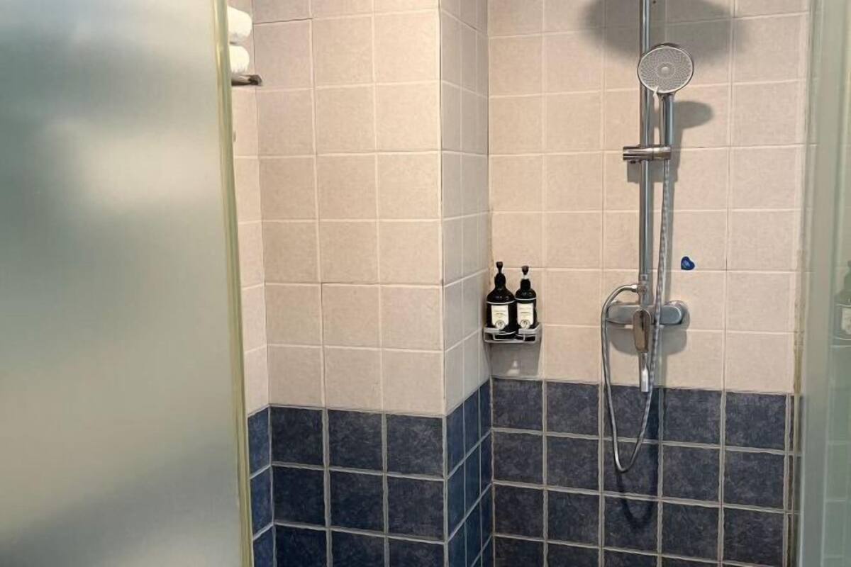 Ducha con cabezal de ducha manual y soporte para botellas.