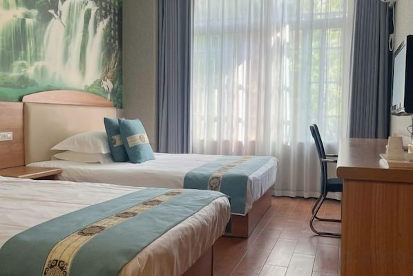 A hotel room with two beds, a desk, a chair, and a painting of a waterfall on the wall. - Hangzhou Shujia Hotel (Hangzhou)