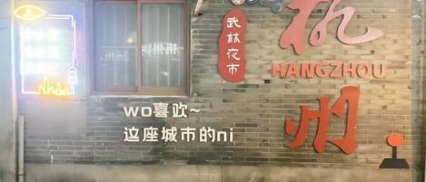 A brick wall with the Hangzhou logo and a neon sign.