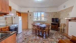 A kitchen with a dining table, chairs, a refrigerator, a stove, and a television.