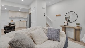 Een moderne woonkamer met een groot bed, een eethoek en een keuken op de achtergrond.