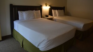 A hotel room with two single beds, each with white bedding and a wooden headboard. There is a nightstand between the beds with a lamp. - #29- TWO QUEEN BEDS in Charming hotel in C. Falls with WiFi, AC, 20 mi to GNP (Columbia Falls)