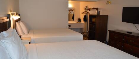 A hotel room with two beds, a dresser, a television, and a mirror.