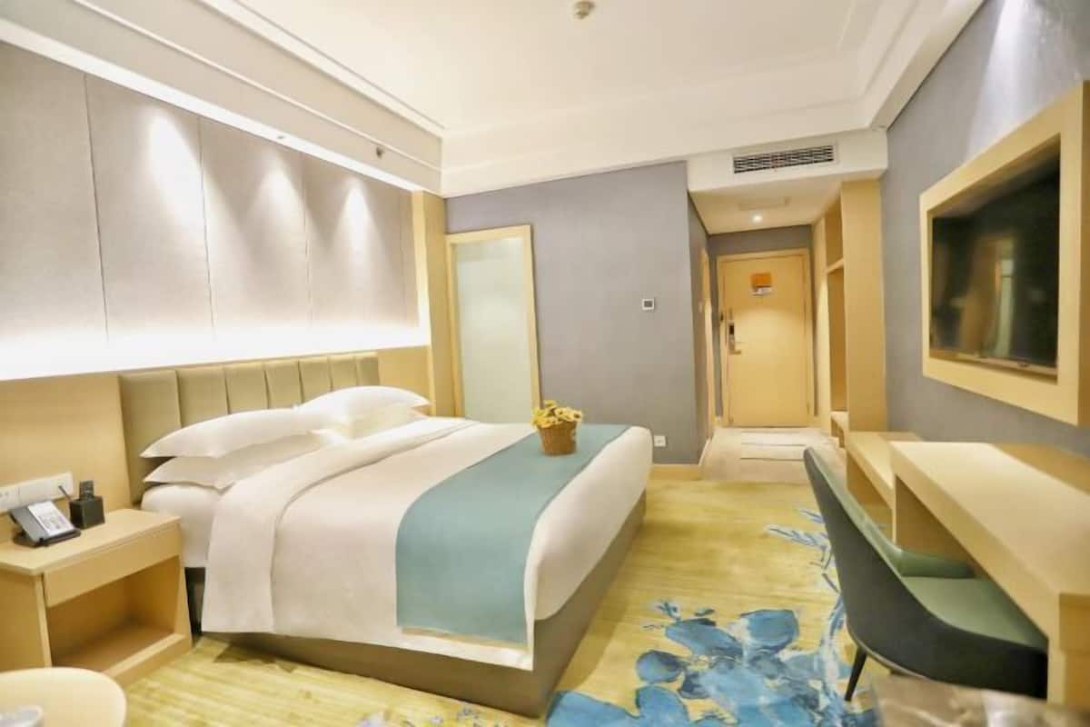 Una habitación de hotel con cama, mesita de noche, escritorio, silla y espejo.