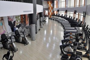 A gym with treadmills, stationary bikes, and elliptical machines arranged in rows. - Guomao Hotel (Yueyang)