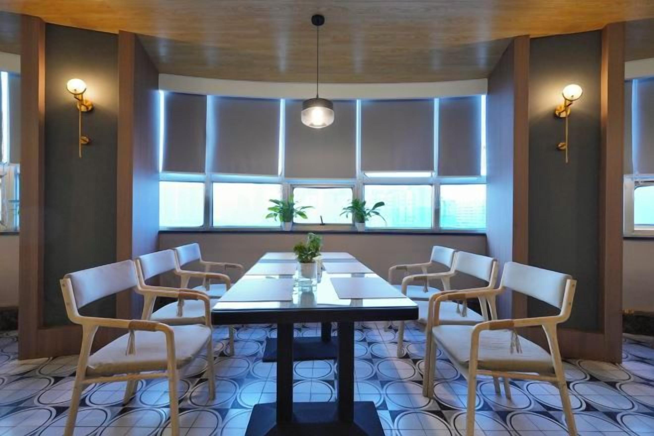 A conference room with a long table, six chairs, and a potted plant.