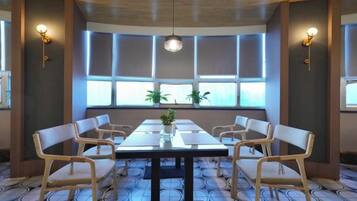 A conference room with a long table, six chairs, and a potted plant.