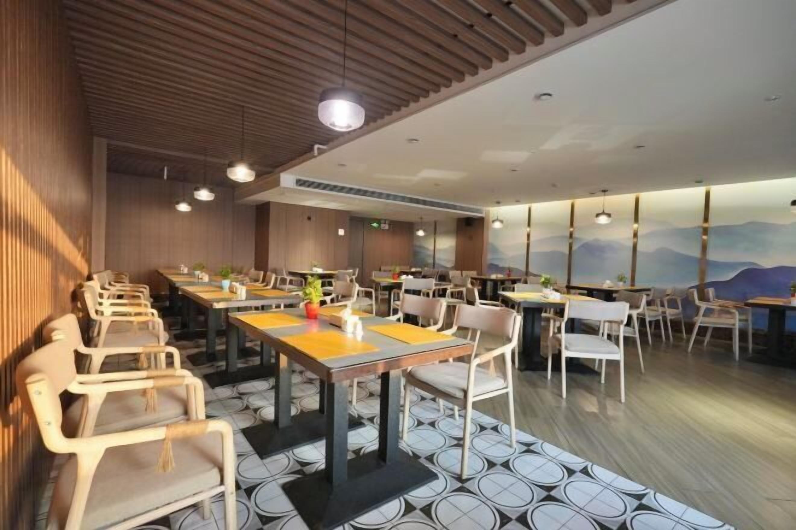 A restaurant with multiple tables and chairs, wooden ceiling, and a mural on the wall.