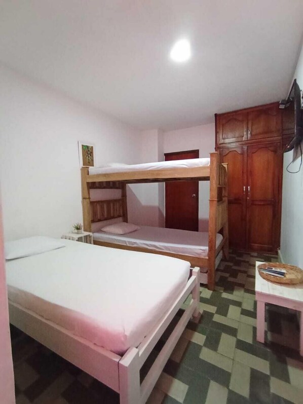 Una habitación con literas, una mesita, un armario y un televisor.