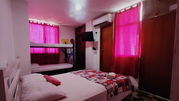 A bedroom with bunk beds, a single bed, a TV mounted on the wall, and a wardrobe. - HOTEL HABIBI (Barranquilla)
