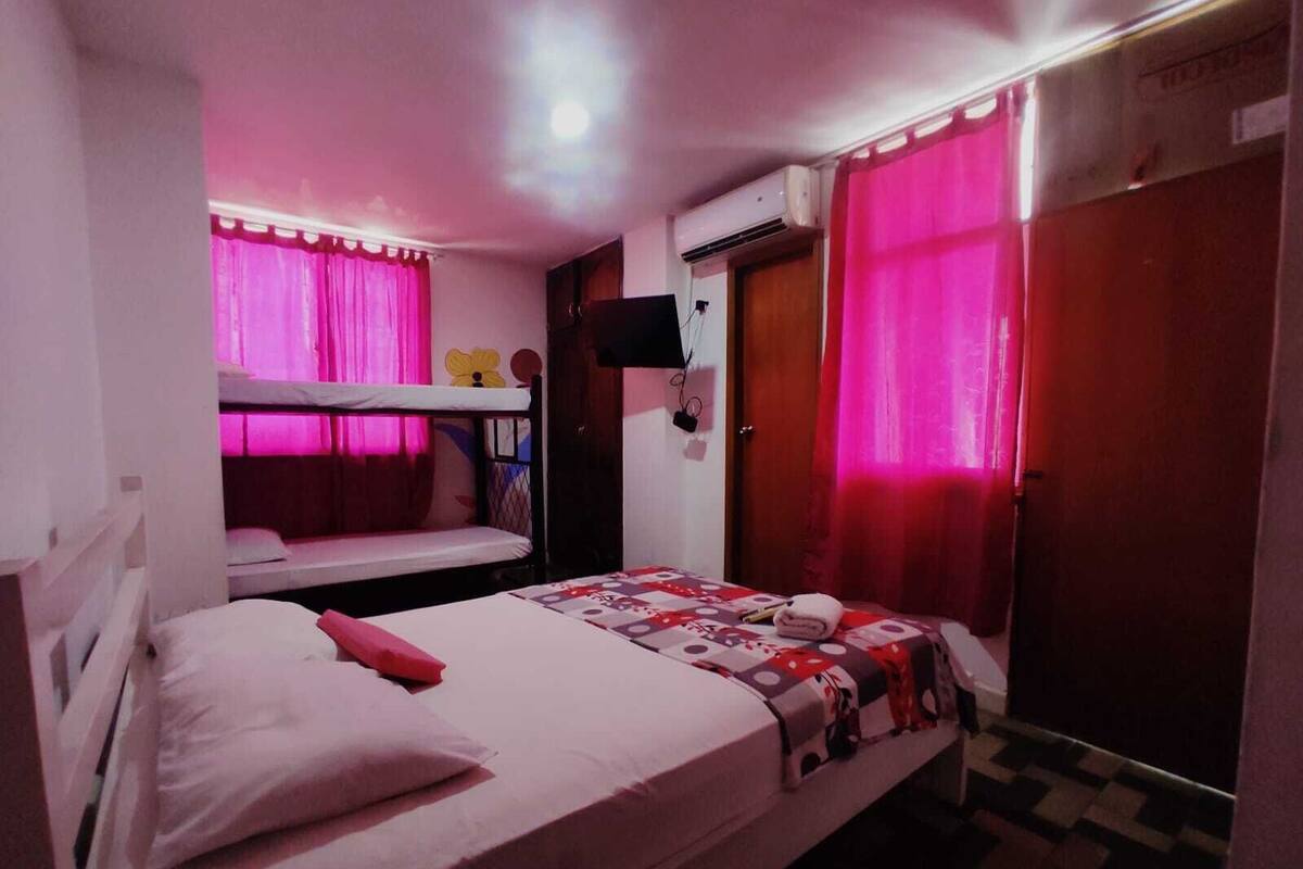 Un dormitorio con literas, una cama individual, un televisor montado en la pared y un armario.