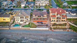 A coastal residential area with houses, a swimming pool, and a rocky beach. - Oceanfront Getaway | Ocean Views, Fire Pit, BBQ, Beach Access (Carlsbad)