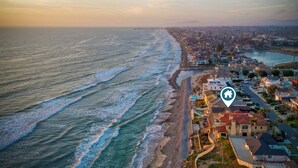 An aerial view of a coastal town with a beachfront, residential buildings, and a clear sky. - Oceanfront Getaway | Ocean Views, Fire Pit, BBQ, Beach Access (Carlsbad)
