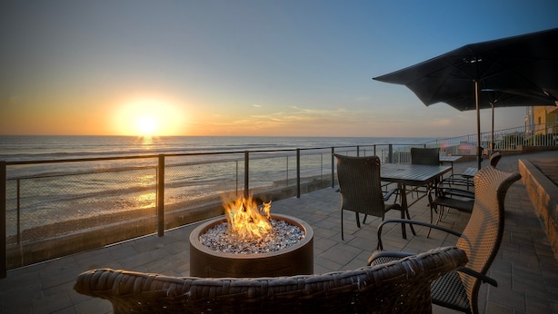 Una chimenea con vistas al océano al atardecer, asientos exteriores y una barandilla.