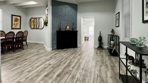 Un salon spacieux doté d’une cheminée, d’un plancher en bois et d’un coin repas avec des chaises.