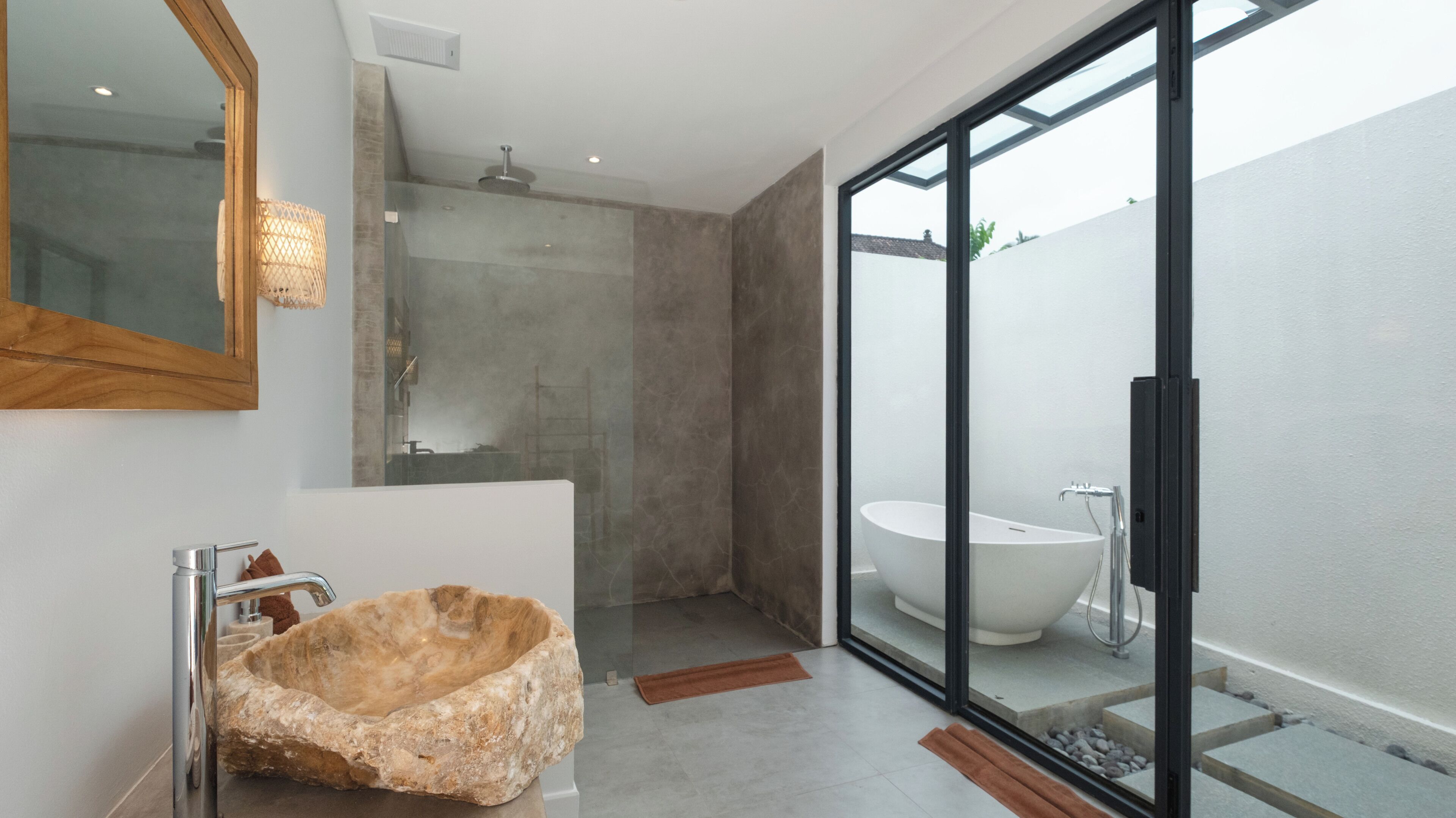 Un bagno moderno con un lavabo di pietra grande, una vasca freestanding e una zona doccia vetrata.
