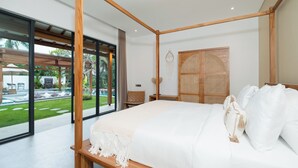 Een moderne slaapkamer met een groot bed, houten balken, een rieten kast en uitzicht op een zwembad en tuin.