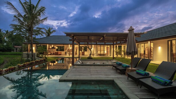 Een modern huis met een zwembad, buitenmeubels en een overdekt terras.