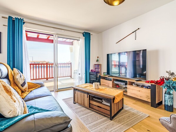 A modern living room with a sofa, coffee table, TV, and a balcony with red railings.