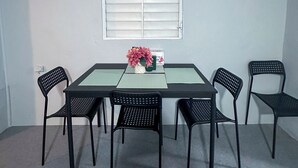 A dining area with a table and six chairs, a window with blinds, and two framed pictures on the wall.