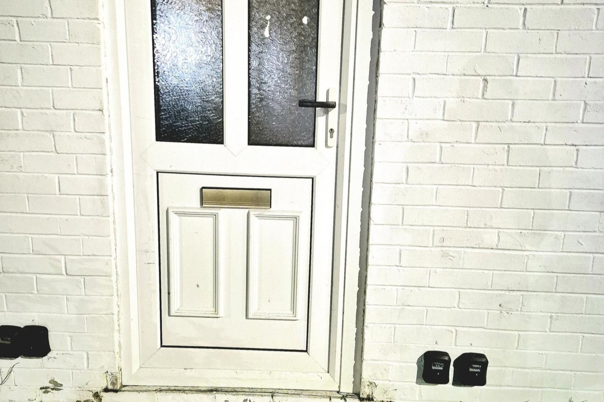 A white door with a brass mail slot and a glass panel above it.