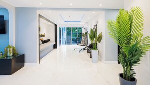 Un hall d’hôtel moderne, doté d’un sol propre et ciré, d’un espace salon avec un canapé et des fauteuils, et d’une grande plante en pot.