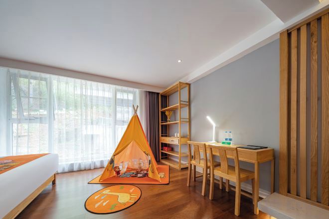 A room with a bed, a desk, a chair, a bookshelf, and a tent-like play area.