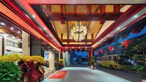 A hotel entrance with a red carpet, a yellow bus outside, and a chandelier. - Shanshui Tingyuan Hotel (Zhangjiajie National Forest Park Wulingyuan Sign Store) (Zhangjiajie)